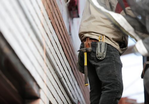 Close-up of a construction worker with hammer and tools, focused on the job.